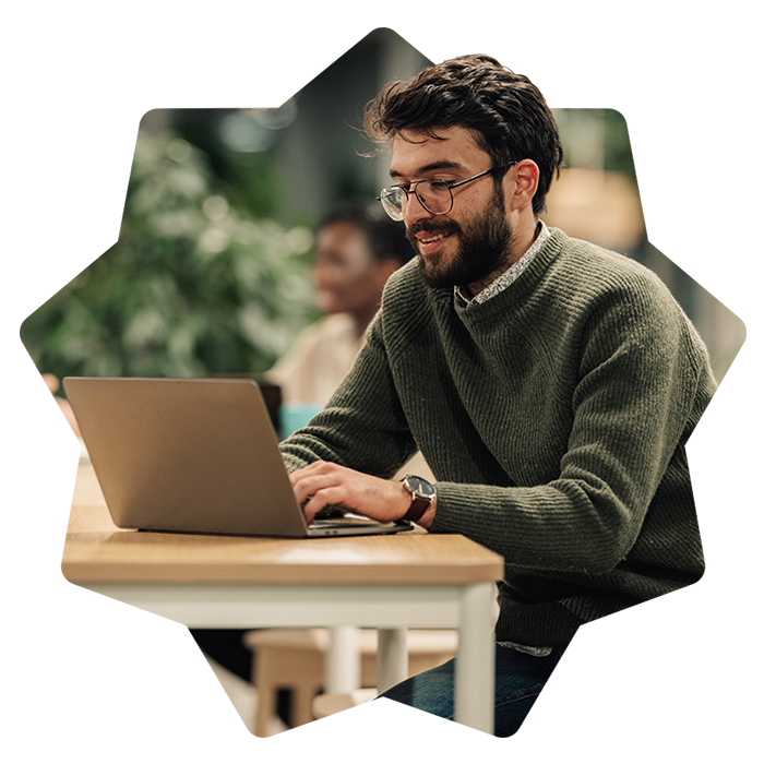 Man looking down at the laptop in office smiling