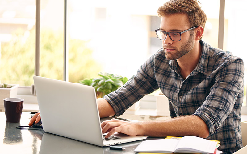 Man with glasses working on a laptop