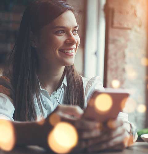 Lady looking out of the window while holding a phone