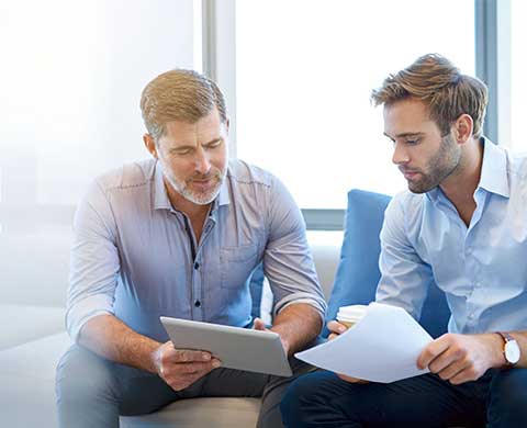 Two men looking at paperwork and a tablet