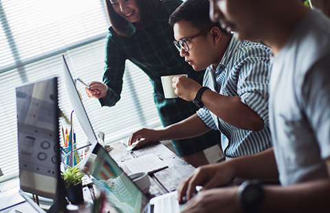 Young professionals gathered around a computer