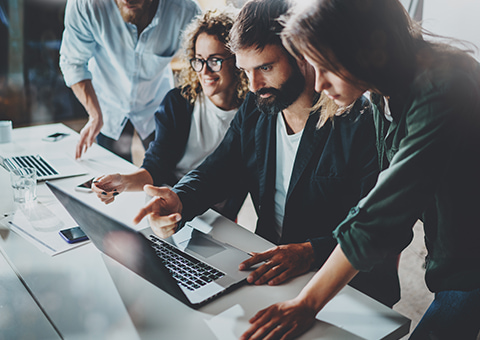 Group of IT professionals gathered around a laptop