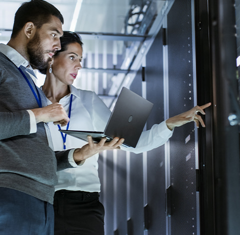 Two IT workers using a laptop in a data centre