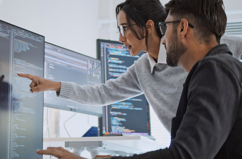 Software engineers collaborating on coding projects at home office using computers.