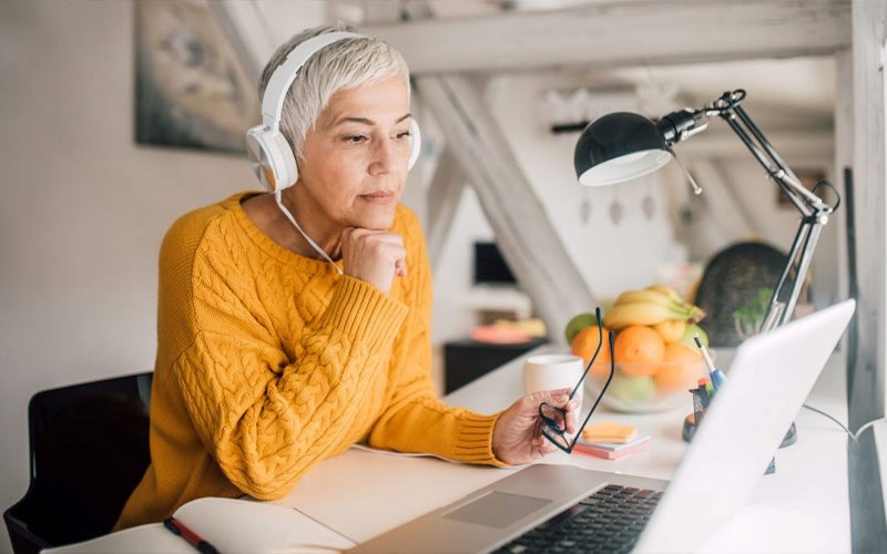 Woman working on laptop while wearing headphones
