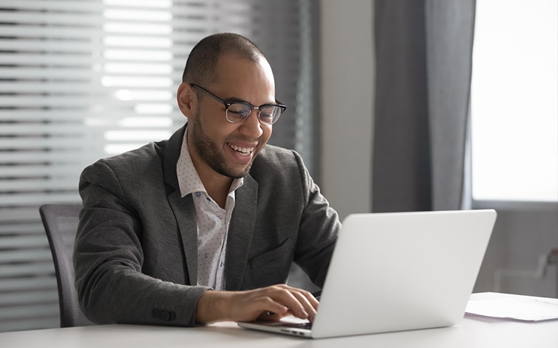 Business man smiling while working on a laptop